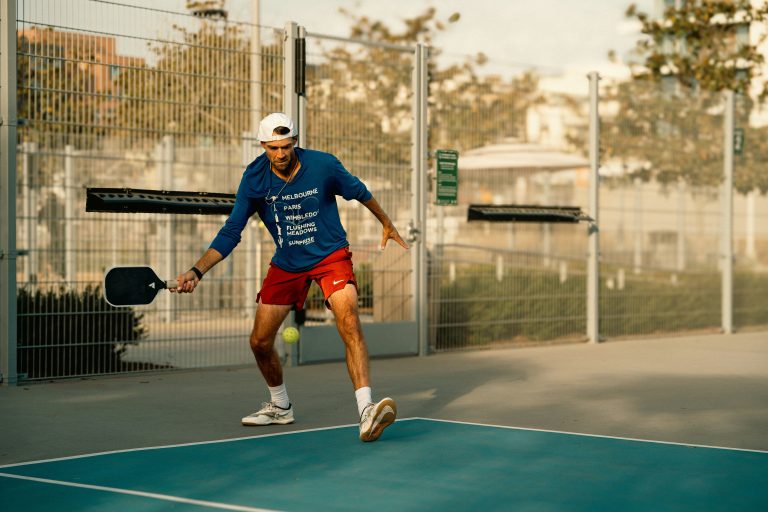 Pickleball player hitting a spin shot with paddle on outdoor court