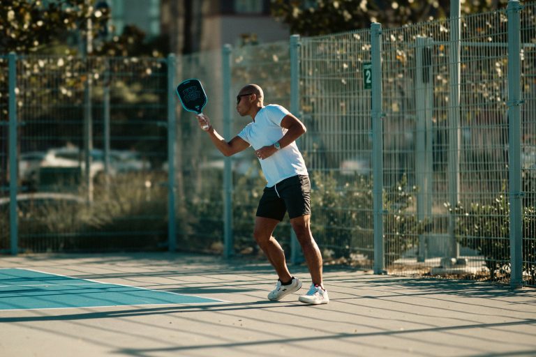 advanced pickleball player hitting a shot with paddle on outdoor sunny court