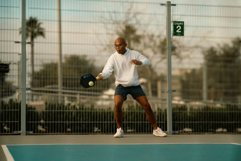 Pickleball player hitting a pickleball with their pickleball paddle for control on an outdoor court