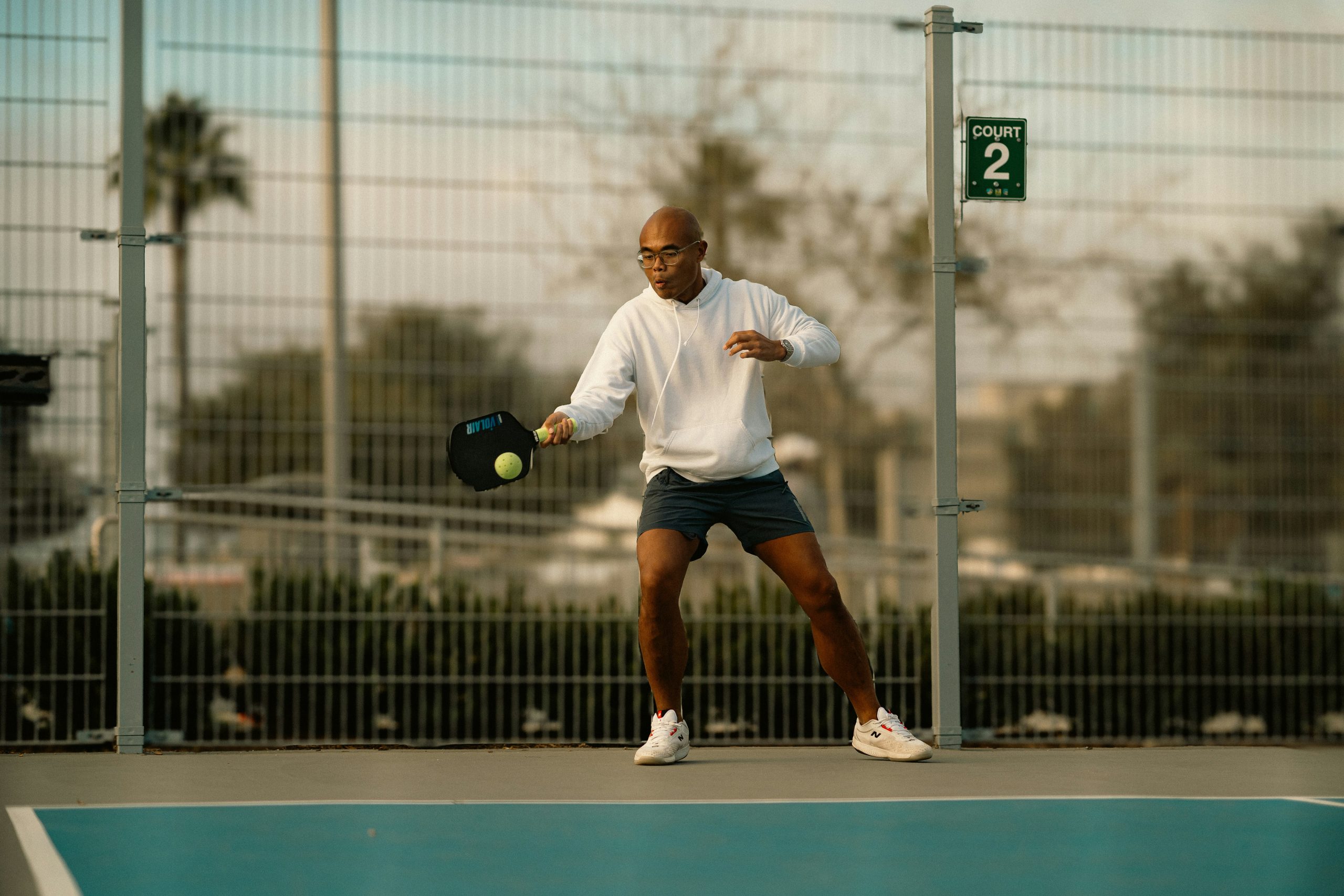 Pickleball player hitting a pickleball with their pickleball paddle for control on an outdoor court